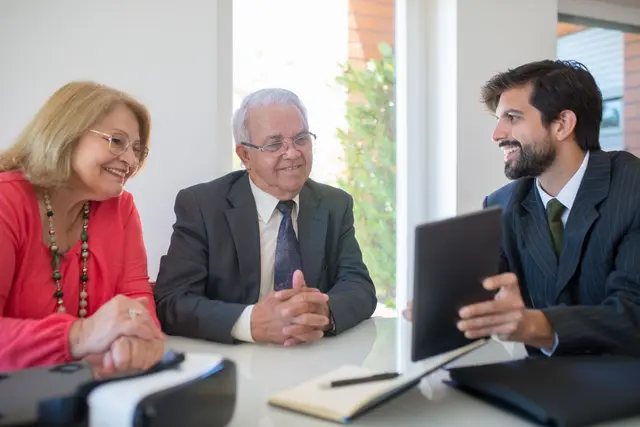 A senior couple talking with their adviser in a bright office