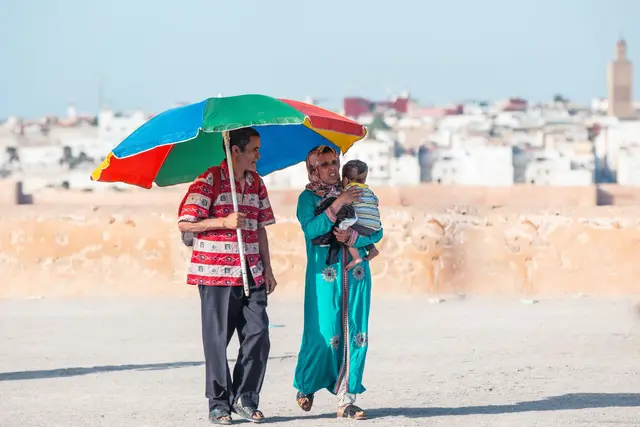 A family with a small child sheltering under a bright umbrella